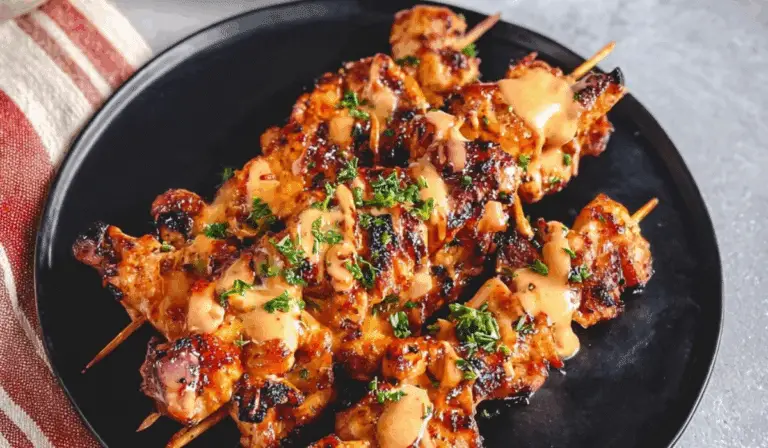 Bang Bang Chicken Skewers grilled and served on a black plate with garnish