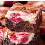 Raspberry Cheesecake Brownies stacked on a rustic table