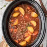 A hearty bowl of Poor Man's Stew with ground beef, potatoes, and carrots, served with buttered bread.