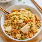A colorful bowl of Better-Than-Takeout Chicken Fried Rice with green onions and chopsticks, showcasing the delicious ingredients.