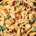 Creamy Tuscan chicken pasta garnished with herbs and Parmesan cheese in a bowl, showcasing a delicious one-pot Italian meal.