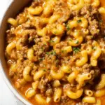 Bowl of homemade hamburger helper with cheesy sauce and macaroni topped with parsley.